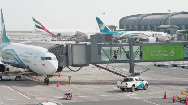 Muscat, Oman - 6 maj 2019: Flygplatspassagerare går ombord på ett plan, folk går genom jetbron. Även kallad jetway, jetwalk, airgate, gangway, aerobridge, airbridge, skybridge, airtube, eller dess — Stockvideo