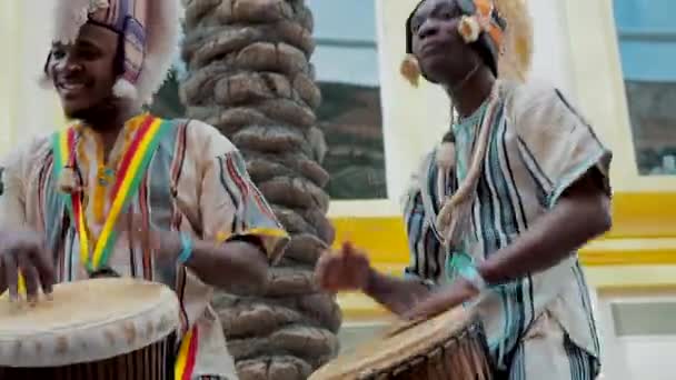 MOSCOW, RUSSIA- FEBRUARI 29, 2020: Afrikaanse drummers in etnische kleding spelen op djembe drum close-up. Muzikant verslaat ritme op Afrikaanse drums. Zwarte artiesten slaan de drums met hun handen — Stockvideo