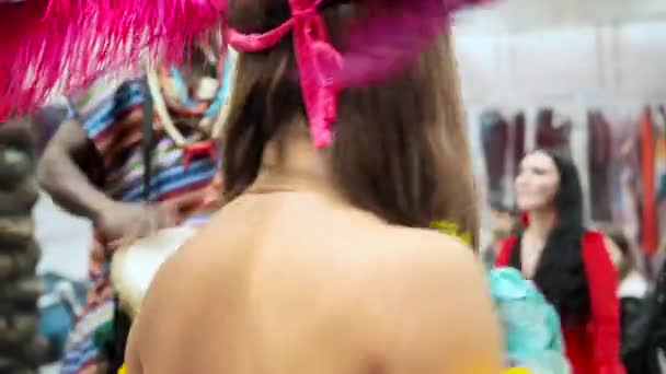 MOSKW, RUSJA - LUTY 29, 2020: Obchody brazylijskiego karnawału w Moskwie. Piękna tancerka tańczy sambę. sexy brunetka dziewczyna w jasne ubrania i pióro headress taniec na karnawał — Wideo stockowe