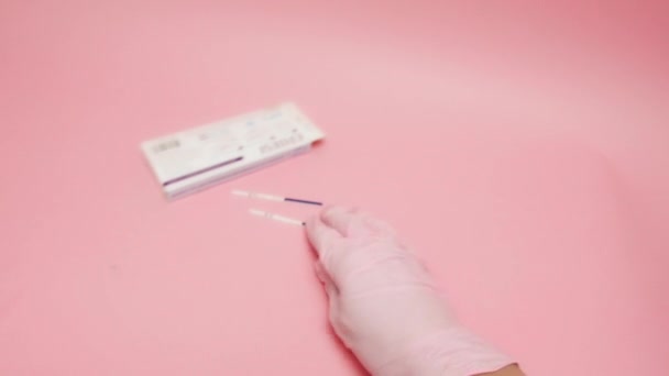 여성 손에 분홍색 의료 장갑을 끼고 양성 임신 테스트를 들고 핑크 배경에서 분리 된 제스처 OK 를 보여 주고 있다. 파란색 막대에 있는 HCG 라는 약어는 인간의 코로 닉 고도 트로 핀이 — 비디오