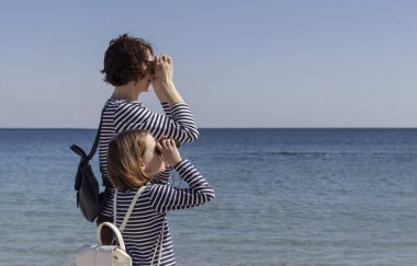 Çocuklu anneler sahilde yürümek. Kız kardeş (8 ve 7 yaşında