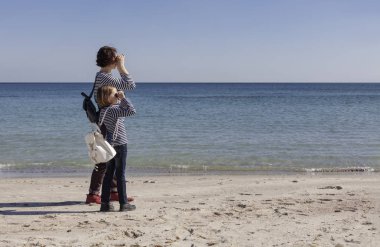 Çocuklu anneler sahilde yürümek. Kız kardeş (8 ve 7 yaşında