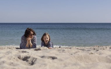 Çocuklu anneler sahilde yürümek. Kız kardeş (8 ve 7 yaşında