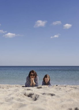Çocuklu anneler sahilde yürümek. Kız kardeş (8 ve 7 yaşında