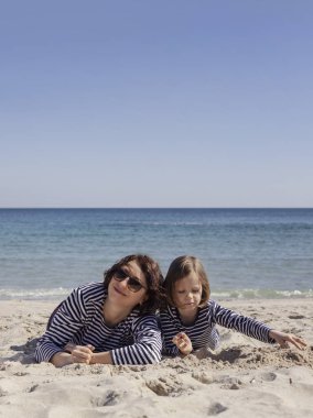 Çocuklu anneler sahilde yürümek. Kız kardeş (8 ve 7 yaşında