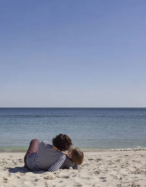 Çocuklu anneler sahilde yürümek. Kız kardeş (8 ve 7 yaşında