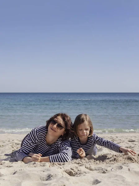 Çocuklu anneler sahilde yürümek. Kız kardeş (8 ve 7 yaşında