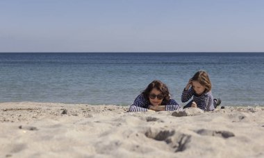 Çocuklu anneler sahilde yürümek. Kız kardeş (8 ve 7 yaşında