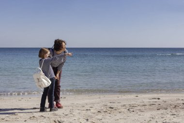 Çocuklu anneler sahilde yürümek. Kız kardeş (8 ve 7 yaşında