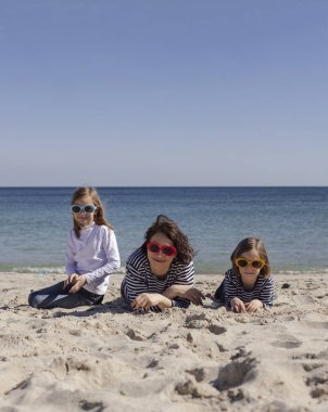 Çocuklu anneler sahilde yürümek. Kız kardeş (8 ve 7 yaşında