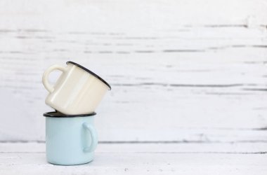 Eski ahşap arka planda retro tarzda emaye kupalar. 