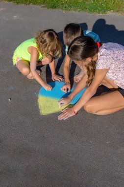 Çocuklar tebeşirle bir kalp çizer ve onu mavi ve sarıya boyarlar