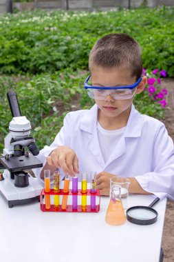 Bilim deneyleri yapan bir çocuk. Mikroskobu olan çocuk.