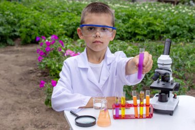 Bilim deneyleri yapan bir çocuk. Mikroskobu olan çocuk.