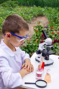 Bilim deneyleri yapan bir çocuk. Mikroskobu olan çocuk.