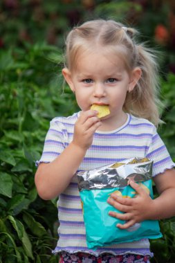 Cips yiyen kız. Sağlıksız yemek ve yaşam tarzı kavramı. Bir paket patates cipsi.