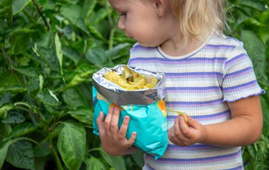 Cips yiyen kız. Sağlıksız yemek ve yaşam tarzı kavramı. Bir paket patates cipsi.