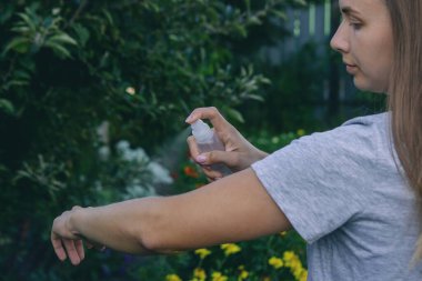 Eline böcek ilacı sıkan bir kadın. Sivrisinek ısırıklarını önleme kavramı.