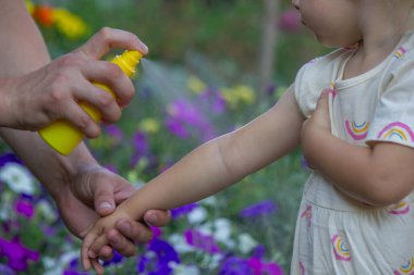Babam çocuğun eline böcek kovucu sprey sıkıyor. Seçici odak.