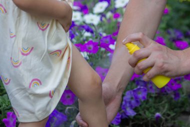 Babam çocuğun eline böcek kovucu sprey sıkıyor. Seçici odak.