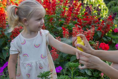 Babam çocuğun eline böcek kovucu sprey sıkıyor. Seçici odak.