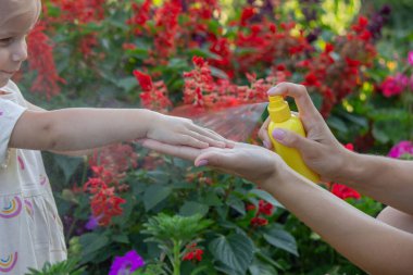 Babam çocuğun eline böcek kovucu sprey sıkıyor. Seçici odak.