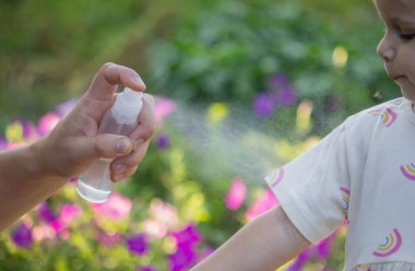 Babam çocuğun eline böcek kovucu sprey sıkıyor. Seçici odak.