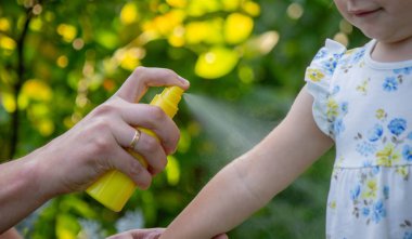 Babam çocuğun eline böcek kovucu sprey sıkıyor. Seçici odak.