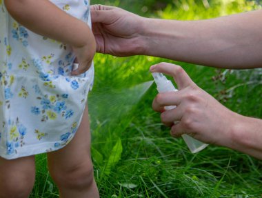 Babam çocuğun eline böcek kovucu sprey sıkıyor. Seçici odak.
