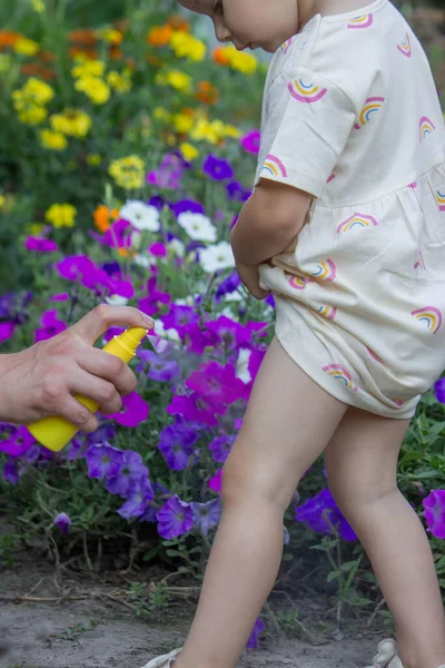 Babam çocuğun eline böcek kovucu sprey sıkıyor. Seçici odak.