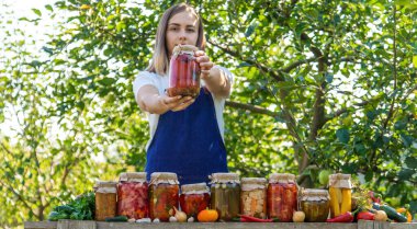 Doğanın arka planında salatalık konservesi yapan bir kadın. Seçici odak.