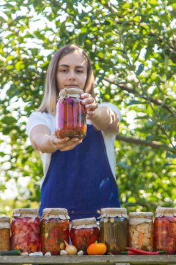 Doğanın arka planında salatalık konservesi yapan bir kadın. Seçici odak.
