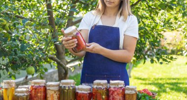Doğanın arka planında salatalık konservesi yapan bir kadın. Seçici odak.