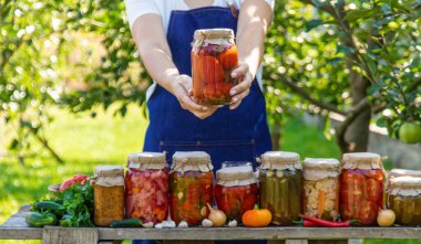 Doğanın arka planında salatalık konservesi yapan bir kadın. Seçici odak.