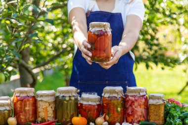 Doğanın arka planında salatalık konservesi yapan bir kadın. Seçici odak.