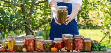 Doğanın arka planında salatalık konservesi yapan bir kadın. Seçici odak.