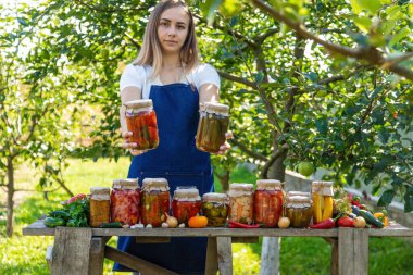 Doğanın arka planında salatalık konservesi yapan bir kadın. Seçici odak.