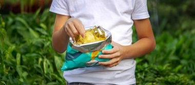Paketten cips yiyen bir çocuk. Sağlıksız gıda konsepti.