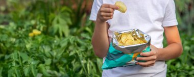 Paketten cips yiyen bir çocuk. Sağlıksız gıda konsepti.