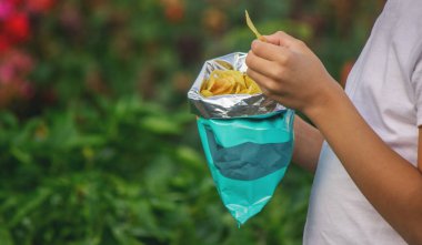 Paketten cips yiyen bir çocuk. Sağlıksız gıda konsepti.