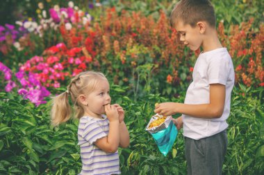 Kız ve erkek paket halinde cips yiyorlar. Çocuk