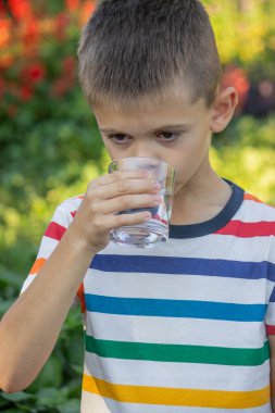 Çocuk dışarıda su içiyor. Seçici odak.