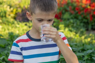 Çocuk dışarıda su içiyor. Seçici odak.