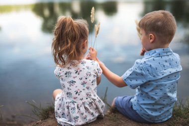 Happy Kids, kız ve erkek göl kenarında oturuyor