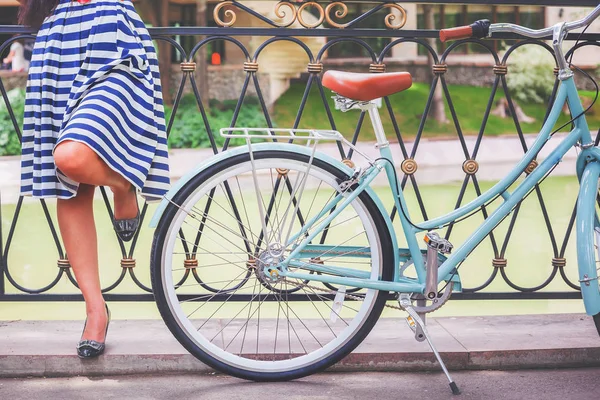 Chica joven de pie cerca de la cerca cerca de la bicicleta vintage en el parque — Foto de Stock
