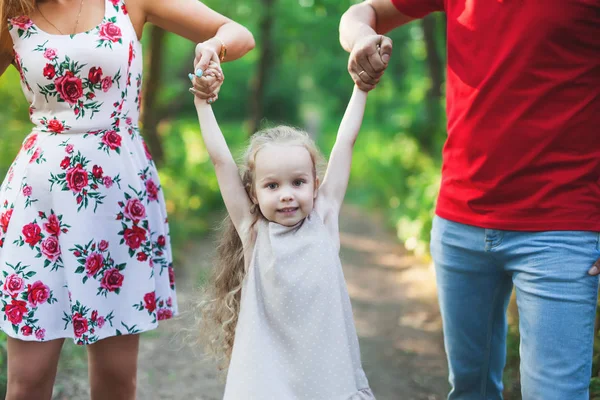 Mamá y papá cogen a su hija de la mano. Familia feliz éxito . —  Fotos de Stock