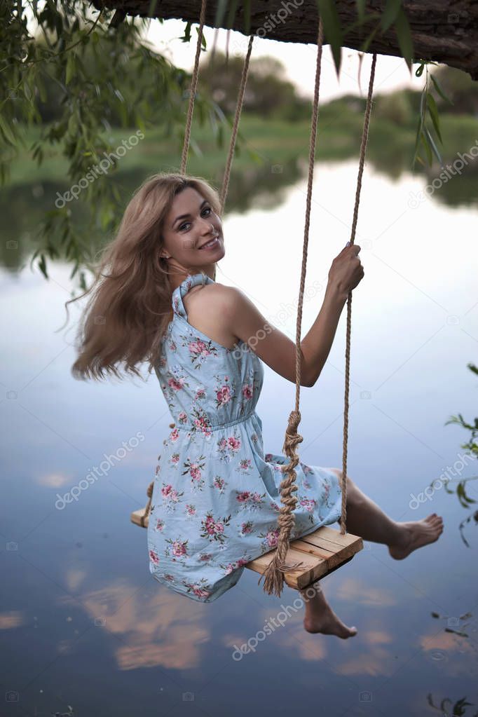 Sexy woman swinging on the swing outdoor. Hair free legs