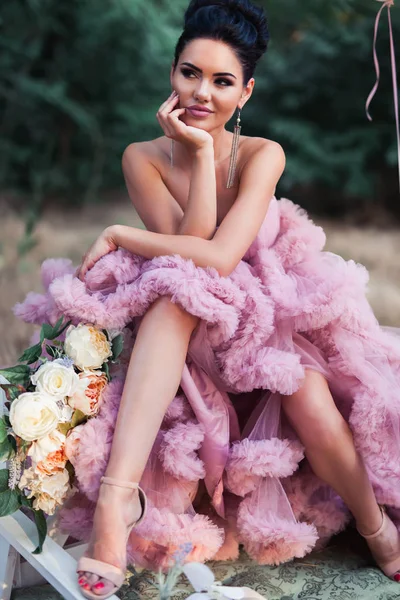 时尚性感的女人穿着粉红色的惊人的礼服包围法国马卡龙 — 图库照片