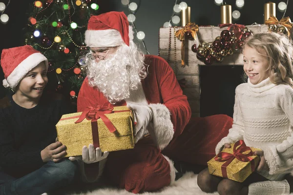 Ευτυχισμένο τον Άγιο Βασίλη και τα παιδιά γύρω από το στολισμένο χριστουγεννιάτικο δέντρο — Φωτογραφία Αρχείου