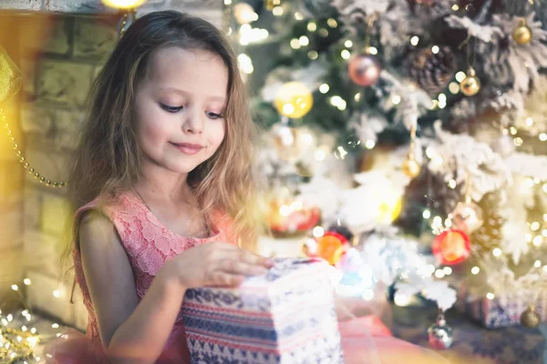 Menina feliz criança descompacta seu presente na noite de Natal . — Fotografia de Stock